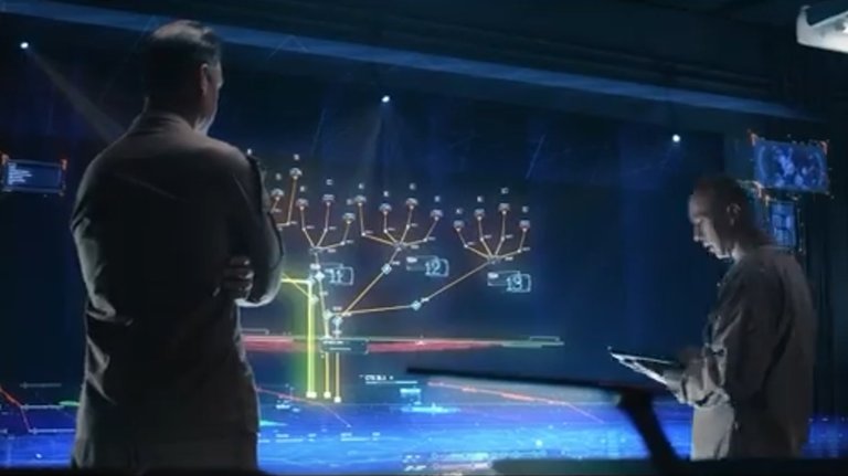 Two sailors stand in front of a computer screen mapping out potential scenarios.