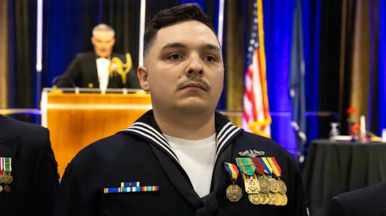 A sailor in a mustache stands with several mustaches